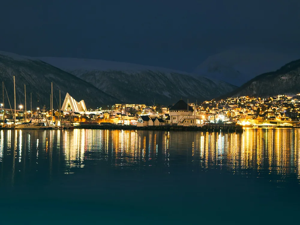 The Arctic Cathedral and the lights of Tromsdalen reflected in the harbour at night